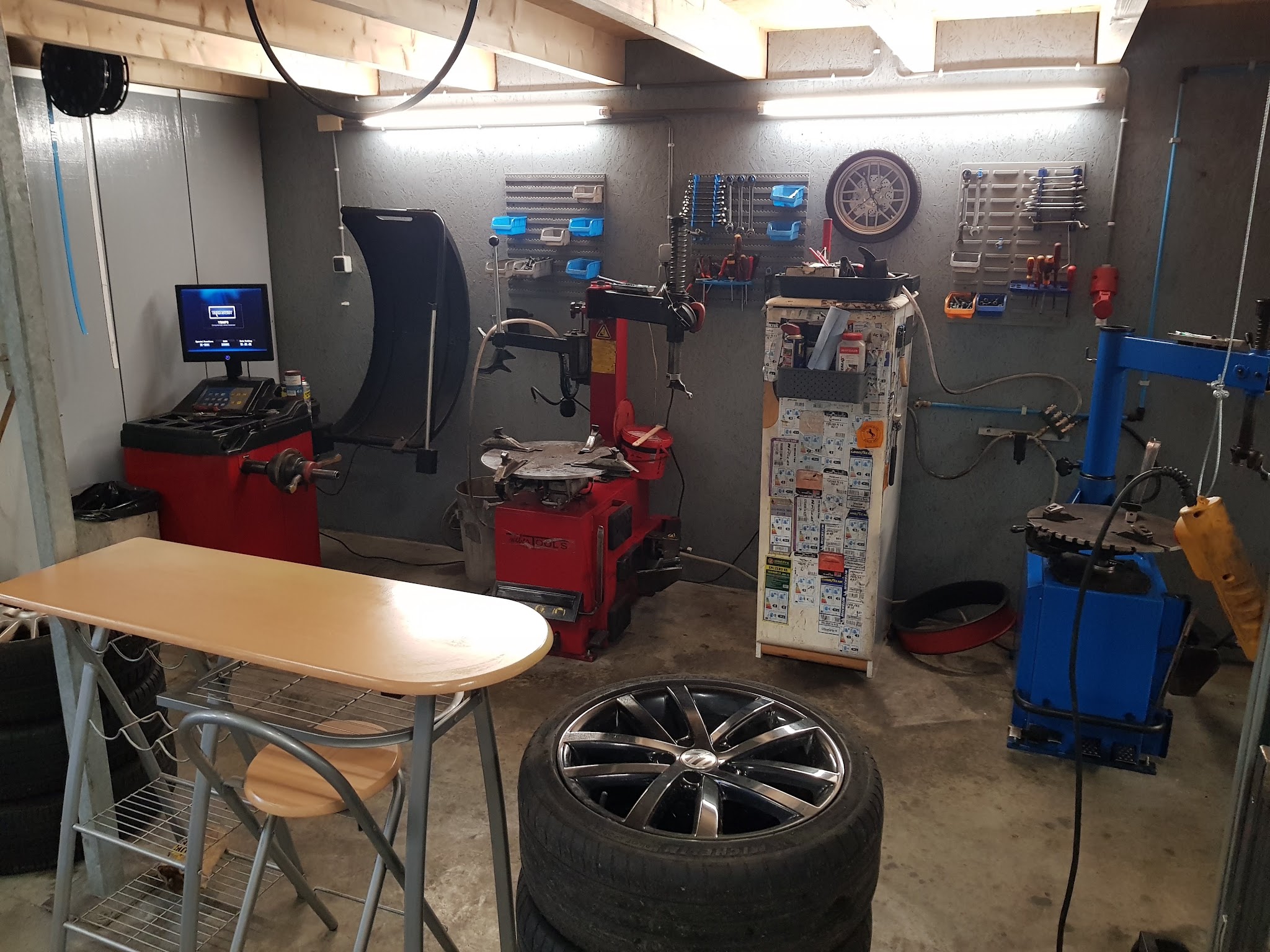 De werkplaats met een rode bandenwisselaar, balanceermachine en gereedschap aan de wand