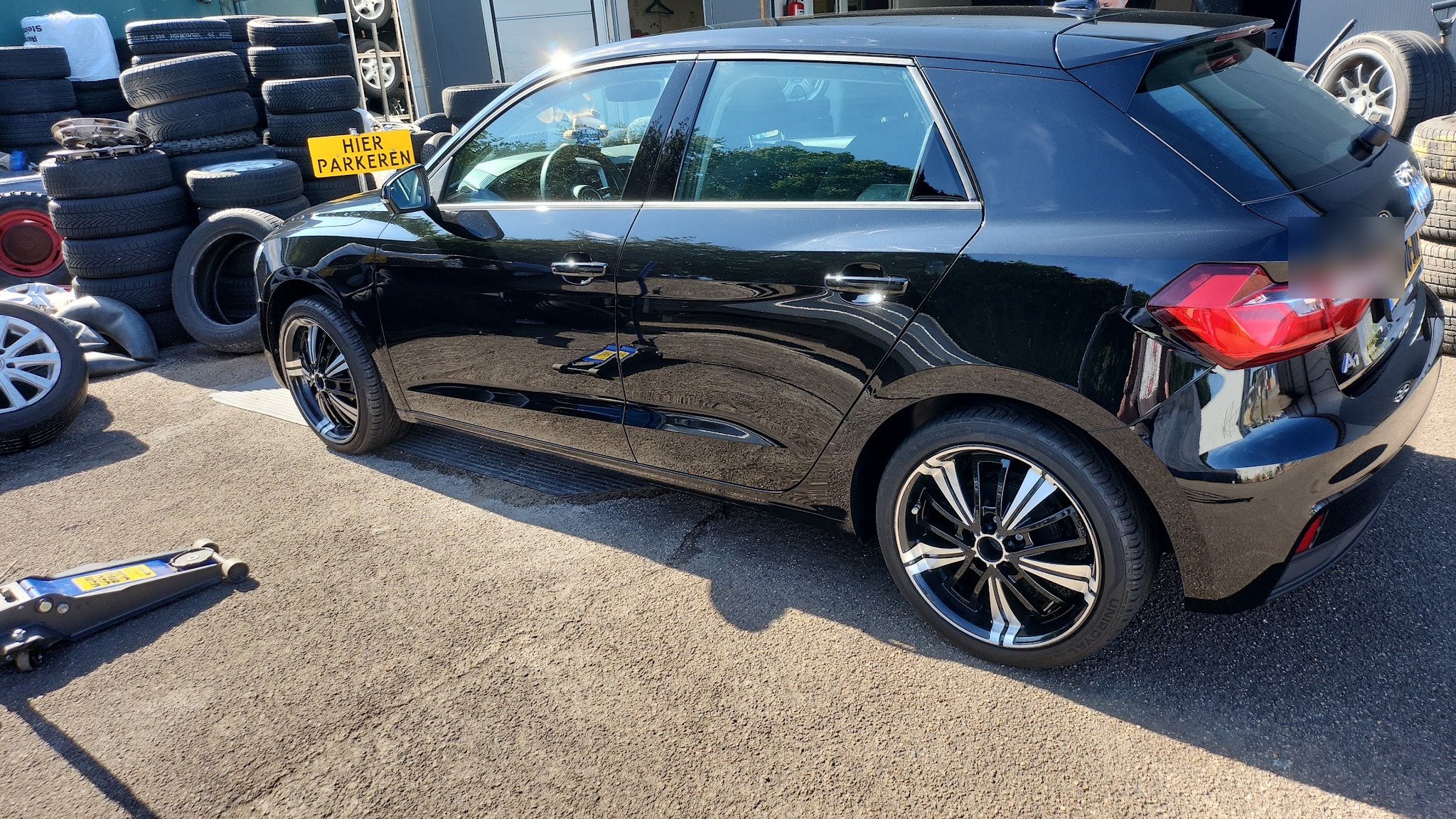 Een zwarte Audi A1 op nieuw gemonteerde lichtmetalen velgen voor de zaak